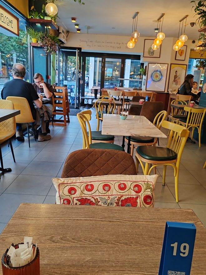 Wooden tables and yellow bentwood chairs under pendant lights.
