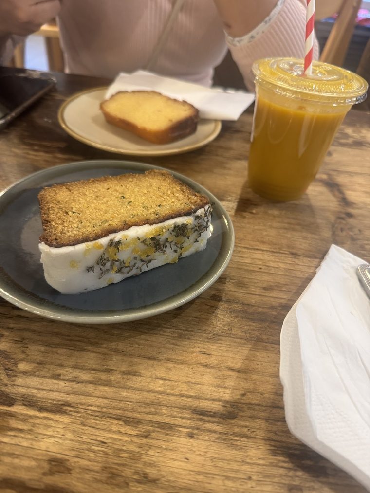 Two slices of iced cake on plates with a glass of orange juice.