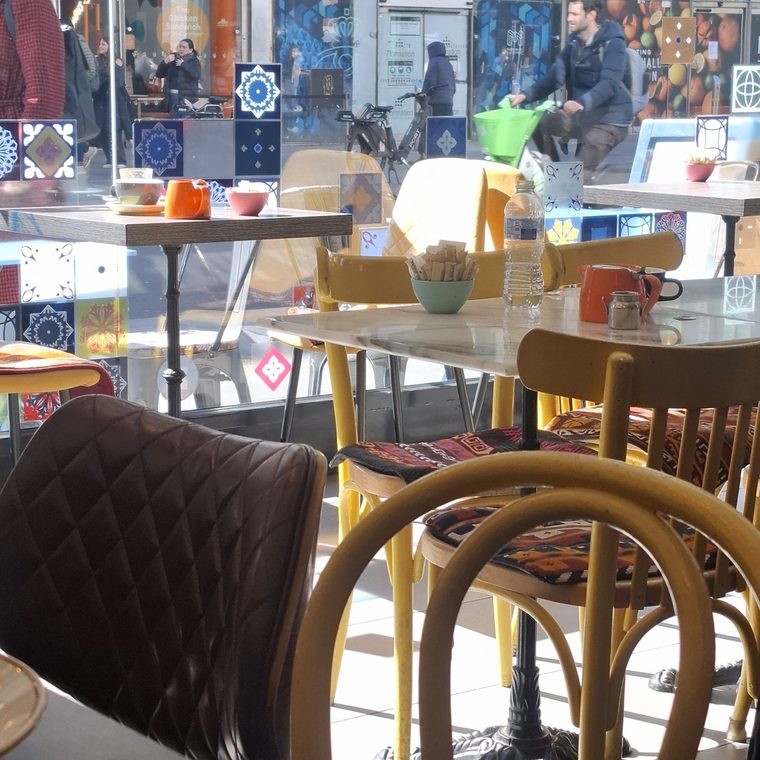 A bowl of fries and coloured mugs on the window table.